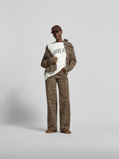 Frauenmodel trägt Oversized T-Shirt aus reiner Baumwolle von Anine Bing mit Label-Print, Halbarm, Rundhalsausschnitt, Ganzkörperansicht von vorne.