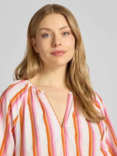 Frauenmodel trägt Regular Fit Bluse mit Raffungen von Emily Van den Bergh in Weiß mit pink-orangenen Streifen, reine Baumwolle, V-Ausschnitt, langärmeliges Design, elastische Ärmelabschlüsse, Nahaufnahme Oberkörper.