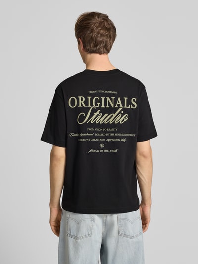 Männermodel trägt Herren T-Shirt mit Statement-Print Modell 'NORREBRO' von Jack & Jones, Schwarztöne, Reine Baumwolle, Gerader-Schnitt, Ganzkörperansicht Rückansicht.
