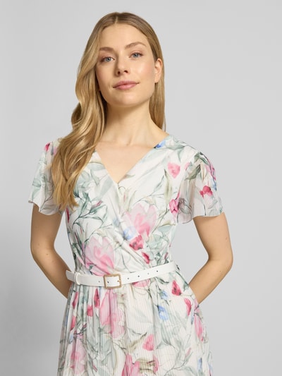 Vrouwenmodel draagt midi-jurk met riem model 'Be44lla' van ZABAIONE met materiaalmix met stretch, getailleerd model, V-hals, wikkellook, vlindermouwen, riem met doornsluiting, rok met plissévouwen, ruglengte maat S 128 cm, borstwijdte 38 cm, mouwlengte 18 cm, bloemenprint in pasteltinten. Nahaufnahme oberkörper.