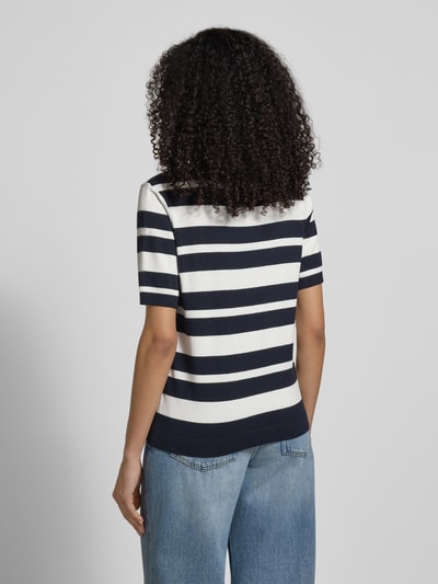 Frauenmodel trägt Strickshirt mit Rundhalsausschnitt und Label-Detail von More & More im Viskose-Elasthan-Mix, navy-weiß gestreift, Regular Fit, mit kurzen Ärmeln und lockerer Jeans, Ganzkörperansicht Rückansicht.