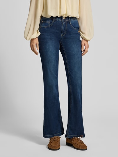 Vrouwenmodel draagt Bootcut Jeans mit Used Look van GANG in medium wash denim met 5-pocket-design en zichtbare stiksels, Nahaufnahme onderlichaam.