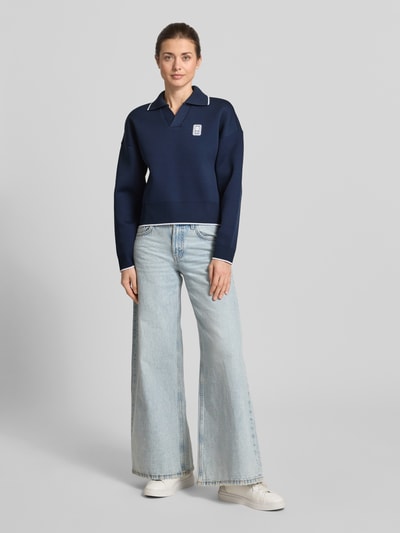 Frauenmodel trägt Regular Fit Sweatshirt mit Kontraststreifen von Lacoste, Optik: Unifarben, Passform: Regular-Fit, Polokragen, V-Ausschnitt, Ärmelform: Langarm, Ärmelabschluss: Gerippt, Rumpfabschluss: Gerippt. Ganzkörperansicht von vorne.