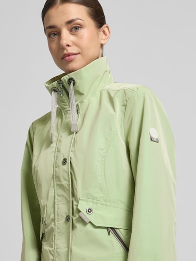 Frauenmodel trägt Regular Fit Jacke mit Logo-Patch von Gil Bret in Pastellgrün mit Stehkragen und Reißverschlusstaschen, Nahaufnahme Oberkörper. Rückenlänge 64 cm, Schulterbreite 41 cm, Brustweite 46 cm, Ärmellänge 65 cm.