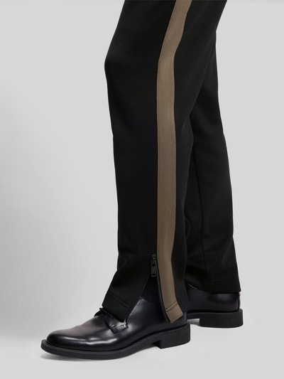 Männermodel trägt Relaxed Fit Jogginghose mit Galonstreifen Modell 'DOLOS' von HUGO, unifarben, Tunnelzug, Sweat, Nahaufnahme Beinbereich.