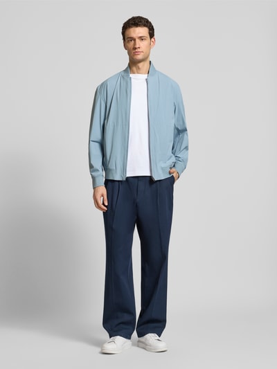 Männermodel trägt Regular Fit Blouson mit Baseball-Kragen Modell 'OSURF' von BOSS Orange in Hellblau, unifarben, glatte Textur, Ganzkörperansicht von vorne.