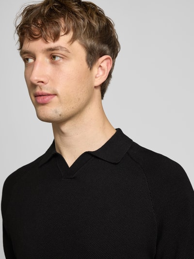 Männermodel trägt Regular Fit Poloshirt mit Strukturmuster Modell 'HILL' von Jack & Jones in Schwarz, Nahaufnahme Oberkörper.