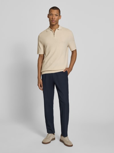 Męski model nosi Regular Fit Poloshirt aus reiner Baumwolle Modell 'CRAN' od SELECTED HOMME, kremowy strukturalny dzianinowy materiał, krótki rękaw, prążkowane wykończenia, kołnierzyk polo, z krótkim zamkiem, krój regular fit, widok całej sylwetki z przodu.