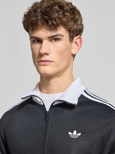 Männermodel trägt Regular Fit Trainingsjacke mit Stehkragen Modell 'Classic' von adidas Originals aus Baumwoll-Mix, Nahaufnahme Oberkörper.