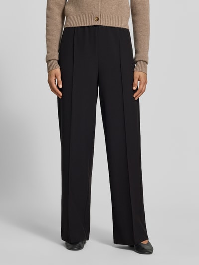 Frauenmodel trägt Wide Fit Sweatpants mit Viskose-Anteil von MYON, Schwarz, Zierfalten, elastischer Bund, glatte Textur, Nahaufnahme Unterkörper.