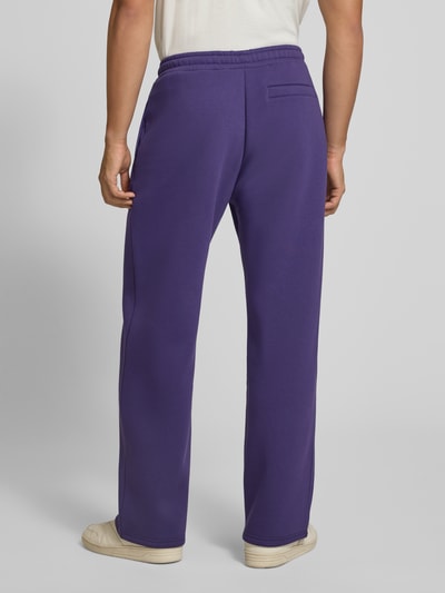 Männermodel trägt Straight Fit Sweatpants aus Baumwoll-Mix mit Label-Detail von REVIEW, kräftiges Lila, glatte Struktur, Ganzkörperansicht Rückansicht.