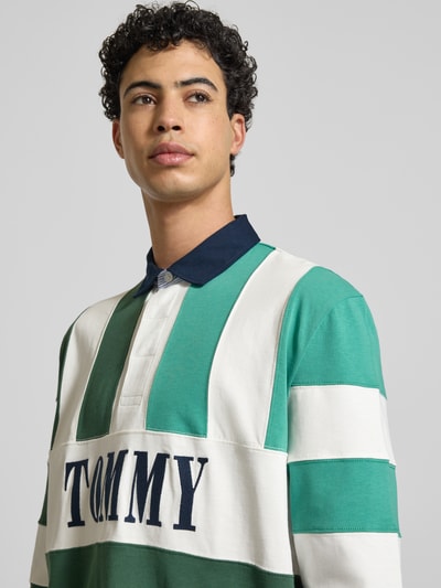 Männermodel trägt Relaxed Fit Poloshirt aus reiner Baumwolle von Tommy Jeans, Optik: mehrfarbig, Label-Schriftzug, Nahaufnahme Oberkörper.