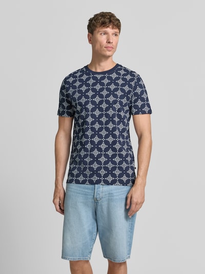 Männermodel trägt Regular Fit T-Shirt aus reiner Baumwolle van s.Oliver RED LABEL in donkerblauw met witte patronen, lichte textuur, Ganzkörperansicht von vorne.