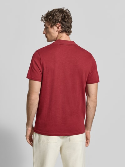 Männermodel trägt Slim Fit Poloshirt mit V-Ausschnitt von MCNEAL in Rot, reine Baumwolle, feine Struktur, Ganzkörperansicht Rückansicht.