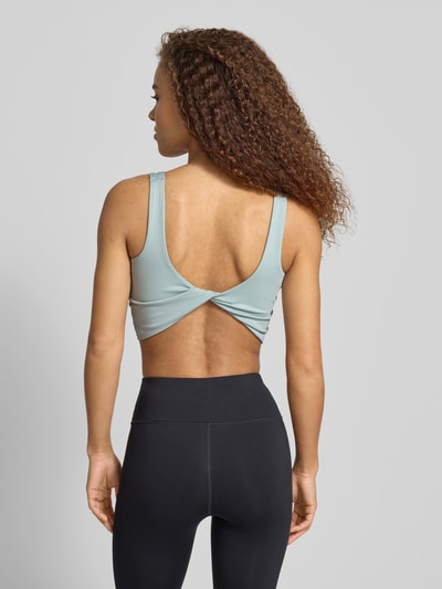Frauenmodel trägt Slim Fit Sport BH mit Logo-Print von adidas Sportswear in Hellblau mit Twist-Optik und Rundhalsausschnitt, Rückenlänge 23 cm, Ganzkörperansicht Rückansicht.