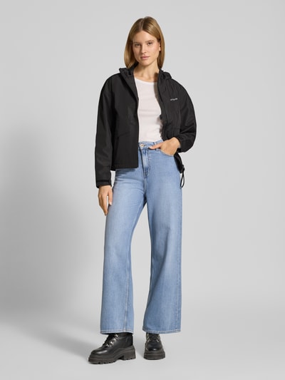 Vrouwenmodel draagt Jacke met Pattentaschen Model 'MILENA' van Didriksons, zwart, recht pasvorm, capuchon, labelprint, geheel zichtbare voorkant, Ganzkörperansicht von vorne.