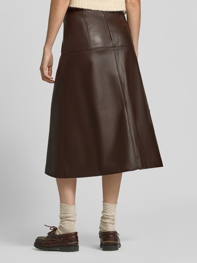 Vrouwenmodel draagt midirok in leerlook van Apricot, donkerbruin, A-lijn, siernaden, naadritssluiting, Bandwijdte maat S 36 cm, totale lengte maat S 78 cm, volledige achteraanzicht.