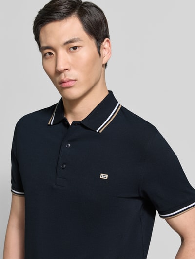 Männermodel trägt Regular Fit Poloshirt mit Kontraststreifen von Christian Berg Men aus Reine Baumwolle, Knopfleiste, Nahaufnahme Oberkörper.