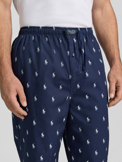 Männermodel trägt Regular Fit Pyjama-Hose aus reiner Baumwolle von Polo Ralph Lauren Underwear, dunkelblau mit weißen Logo-Mustern, Nahaufnahme Oberkörper.