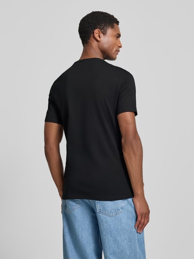 Männermodel trägt T-Shirt mit Logo und Rundhalsausschnitt von GUESS aus Reine Baumwolle in Schwarz, Slim-Fit, Rückenlänge 70 cm, Ganzkörperansicht Rückansicht.