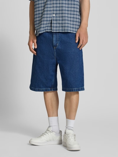 Männermodel trägt Jeansshorts mit Eingrifftaschen Modell 'Brandon' von Carhartt Work In Progress aus Reine Baumwolle, Relaxed-Fit, Ganzkörperansicht von vorne.