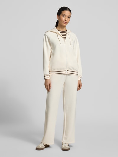 Frauenmodel trägt Regular Fit Sweatjacke aus Viskose-Mix mit Logo-Stitching von ARMANI EXCHANGE in Creme mit Kapuze, Tunnelzug, Reißverschluss, elastische Abschlüsse, Ganzkörperansicht von vorne