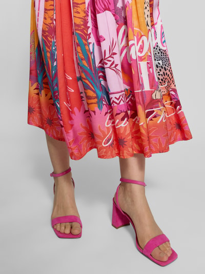 Frauenmodel trägt Midirock aus reiner Viskose mit Allover-Motiv-Print von miss goodlife, kräftige Pink- und Orangetöne, A-Linie, Nahaufnahme Unterkörper. Damen Midirock, elastischer Bund, Bundweite bei Größe S 35 cm, Gesamtlänge 82 cm.