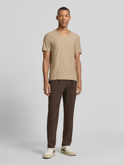 Męski model nosi Regular Fit T-Shirt mit V-Ausschnitt od MCNEAL, bawełna, krój regular fit, dekolt w serek, zrolowany brzeg, długość tyłu 70 cm, rozmiar M, widok całej sylwetki z przodu.
