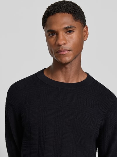 Mężczyzna nosi Regular Fit Pullover aus reiner Baumwolle Modell 'Simoh' od HUGO, ciemny sweter, tekstura dzianiny, Nahaufnahme Oberkörper. Sweter męski HUGO.