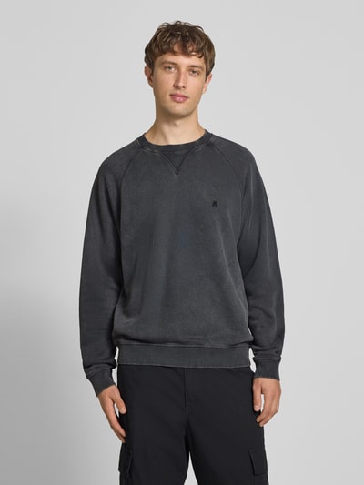 Männermodel trägt Regular Fit Sweatshirt aus reiner Baumwolle Modell 'Plush' von Replay in Dunkelgrau mit elastischen Abschlüssen, Ganzkörperansicht von vorne.