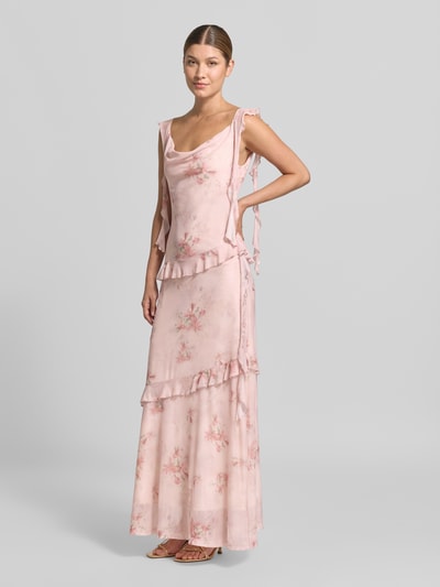 Frauenmodel trägt Maxikleid aus Mesh Modell 'Adelle' von Neo Noir in Rosa mit Allover-Blumenmuster und Rüschen, Ganzkörperansicht von vorne.