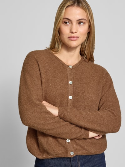 Kobiece model prezentuje kardigan Relaxed Fit Cardigan aus Woll-Alpaka-Mix Model 'VITOW' od American Vintage, mieszanka wełny i alpaki, imitacja dzianiny, listwa guzikowa, okrągły dekolt, brązowy, widoczne faktura materiału, długość tyłu 52 cm, długość rękawów 56 cm, ujęcie: z przodu, zbliżenie na górną część ciała.