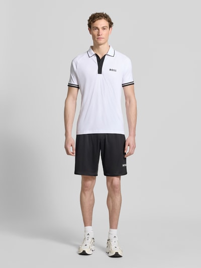 Männermodel trägt Regular Fit Poloshirts mit Kontrastdetails von BOSS Green in Two-Tone-Optik, Polokragen, 2-Knopf-Verschluss, Ganzkörperansicht von vorne.