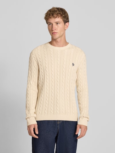 Männermodel trägt Slim Fit Strickpullover reine Baumwolle von REVIEW in Beige mit Zopfmuster und Logo, Ganzkörperansicht von vorne. Rückenlänge bei Größe M 73 cm, Ärmellänge 70 cm, gerippte Bündchen.