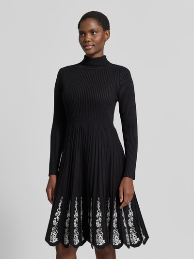 Kobiece modelka nosi Knielanges Strickkleid aus Viskose-Mix von Apricot, czarny, taliowany krój, stójka, efekt prążkowania, krój z długim rękawem, spódnica w kształcie litery a z zakładkami, hafty kwiatowe, długość do kolan, Mieszanka wiskozy, Szerokość w rozmiarze S: 34 cm, Długość tyłu w rozmiarze S: 99 cm, Długość rękawów w rozmiarze S: 60 cm, widok na cały przód