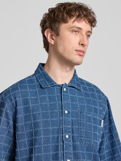 Männermodel trägt Oversized Freizeithemd in Denim-Optik Modell 'Elton' von Redefined Rebel, Baumwolle, Kentkragen, Nahaufnahme Oberkörper.