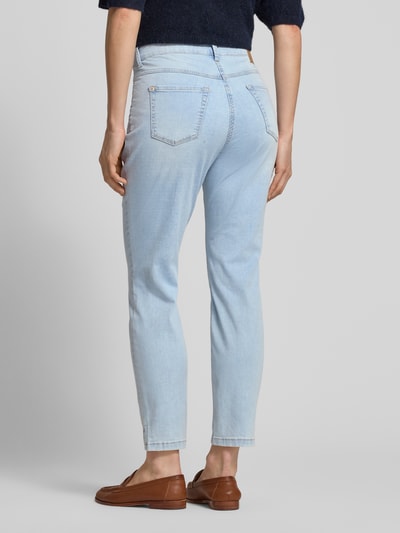 Modelka nosi Slim Fit Jeans aus Baumwoll-Mix Modell 'DREAM SUMMER' od MAC, mieszanka bawełny i modalu, 5 kieszeni, jasnoniebieskie, szwy w kontrastowym kolorze, naszywka z logo z tyłu, skrócony krój, szerokość w rozmiarze 36/28: 39 cm, długość wewnętrzna nogawki: 68 cm, widok całej sylwetki z tyłu.