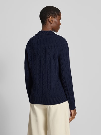 Frauenmodel trägt Pullover aus Wolle mit Polokragen von GANT, dunkelblau, Zopfmuster, Rippbündchen, unifarben, Ganzkörperansicht Rückansicht.