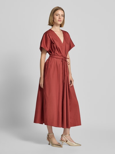 Frauenmodel trägt Cocktailkleid mit V-Ausschnitt und Schnürung von Christian Berg Cocktail aus Baumwoll-Elasthan-Mix in A-Linie, Midikleid, rostrot, leichte Stofftextur, Ganzkörperansicht von vorne.