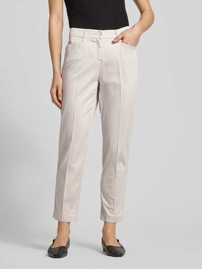 Frauenmodel trägt Hose in verkürzter Passform Modell 'Mara S' von Brax, hellbeige, mit Bügelfalten, Eingrifftaschen, Nahaufnahme Oberschenkel. Baumwoll-Mix mit Lyocell-Anteil.