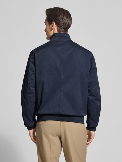 Męski model nosi Jacke mit Stehkragen und Pattentaschen von Christian Berg Men, mieszanka bawełny i elastanu, krój regular fit, długość tyłu w rozmiarze M 32 cm, szerokość ramion w rozmiarze M 41 cm, szerokość w rozmiarze M 55 cm, długość rękawów w rozmiarze M 67 cm, granatowy, gładka faktura, widok całej sylwetki od tyłu.