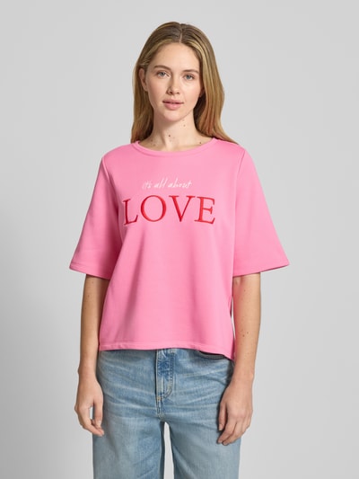 Frauenmodel trägt T-Shirt mit Statement-Stitching von Milano Italy in Pink mit Rundhalsausschnitt, Relaxed-Fit, Material-Mix, Nahaufnahme Oberkörper.