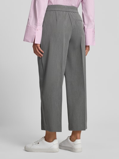 Vrouwenmodel draagt grijze stoffen broek Model 'Cisilia' van someday, materiaalmix met viscose, barrel fit, strookzak achter, achterkant volledig zichtbaar.