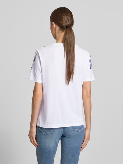 Frauenmodel trägt T-Shirt im Allover-Look mit Pailletten von Marc Cain aus Reine Baumwolle, Regular-Fit, Rundhalsausschnitt, Rückenlänge 59 cm, Ganzkörperansicht Rückansicht.