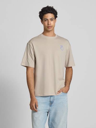 Männermodel trägt Regular Fit T-Shirt aus reiner Baumwolle Modell 'CASPIAN AIRFLEX AMORE' von Only & Sons in Beige, Unifarbe, Rundhals, kurzarm, mit Print, kühlend, atmungsaktiv, Ganzkörperansicht von vorne.