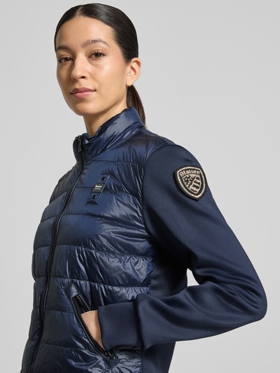 Frauenmodel trägt Steppjacke mit Label-Patches Modell 'HASKEL' von Blauer Usa, dunkelblau, zwei Materialien, Nahaufnahme Oberkörper.