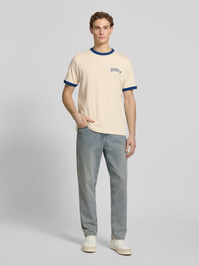 Męskimodel nosi T-Shirt mit Rundhalsausschnitt od Wood Wood z bawełny, krój regular fit, model 'Parker', kontrastowe paski, długość tyłu w rozmiarze M 71 cm, jasny z niebieskimi detalami, pełny widok z przodu.