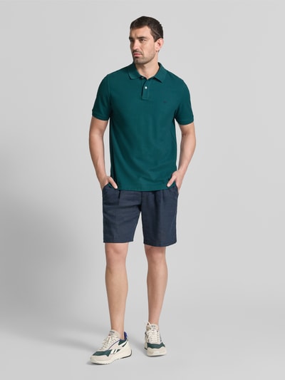 Männermodel trägt Regular Fit Poloshirt mit Label-Stitching von Fynch-Hatton in Grün, reine Baumwolle, Ganzkörperansicht von vorne.