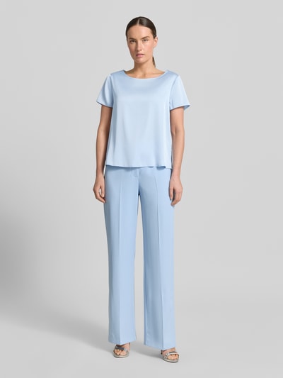 Frauenmodel trägt Blusenshirt mit Rundhalsausschnitt und abgerundetem Saum von Rinascimento, Material-Mix mit Stretch-Anteil, Loose-Fit, Rückenlänge bei Größe S 52 cm, hellblau; Ganzkörperansicht von vorne.