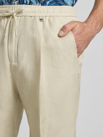 Männermodel trägt Shorts aus Leinen-Viskose-Mix Modell 'NEIL' von Antony Morato in Beige mit Bügelfalten, elastischer Bund, Nahaufnahme Oberkörper. Regular-Fit Design, Kontext: Bundweite bei Größe 50 42 cm, Innenbeinlänge bei Größe 50 17 cm.